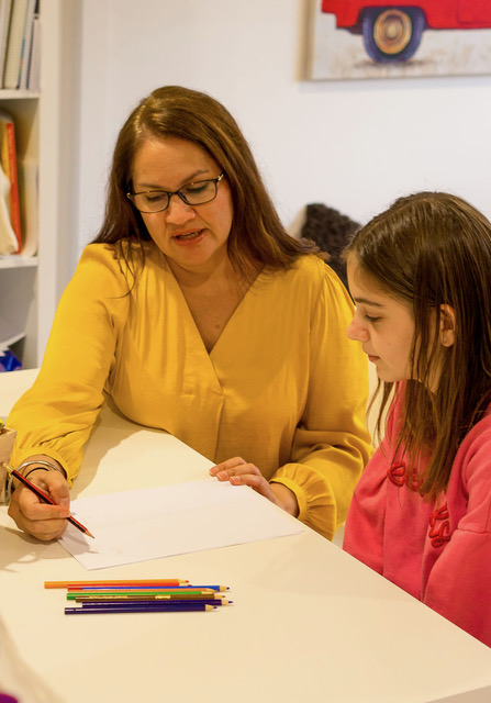 Sim Dhaliwal guiding a child through a writing activity